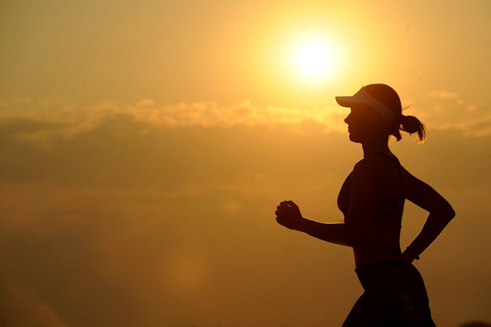 Woman running fitness wearing cap sunset