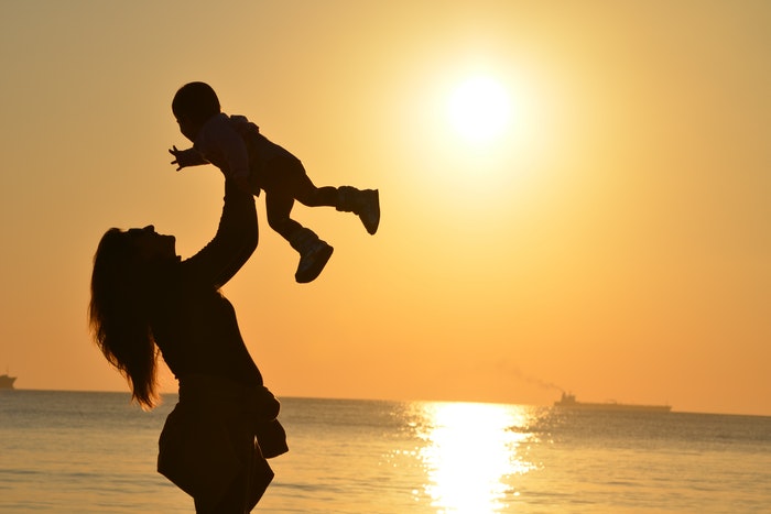 Woman lifting child post-pregnancy sunset